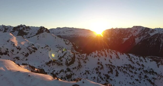 Alpine sunrise at Chamrousse, France with snowed peaks with pine trees on the ridge, Aerial hovering shot