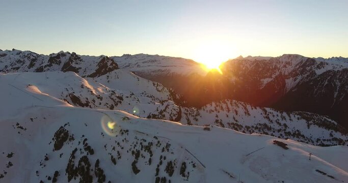 Alpine mountain landscape at Chamrousse, France with beautiful sunrise between the peaks, Aerial orbit right reveal shot