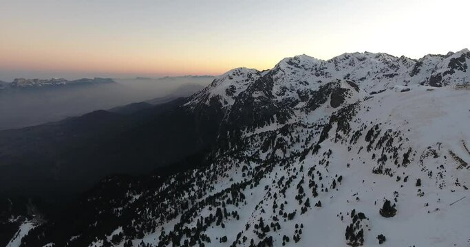 Alpine peaks at Chamrousse France during sunrise with dense fog left, Aerial flyover shot