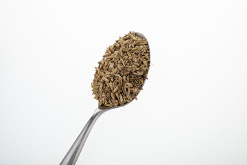 Silver teaspoon with cumin on white background
