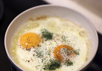 Frying pan with fried egg sprinkled with dill