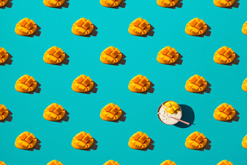 Mango halves and mango smoothie bowl on blue background, pattern. Vegan food concept.