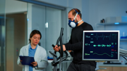 Team of medial researchers monitoring vo2 of man performance sports wearing mask running. Lab...