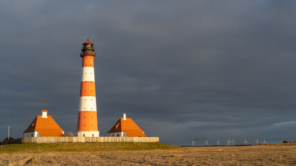 Der Leuchtturm von Westerhever im Sonnenschein mit dunklem Himmel, Schleswig Holstein, Deutschland