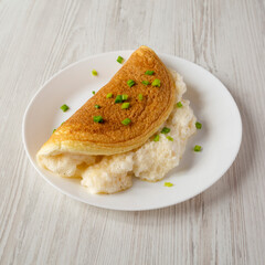 Homemade Fluffy Omelet on a white plate on a white wooden background, low angle view.