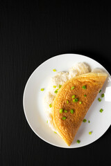 Homemade Fluffy Omelet on a white plate on a black background, top view. Copy space.