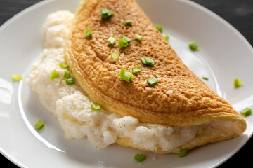 Homemade Fluffy Omelet on a white plate on a black background, side view. Close-up.