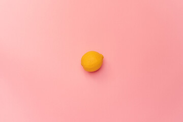 Fresh lemon on a pink background. The lemon in the center of the frame. Minimalism. Minimal cooking concept
