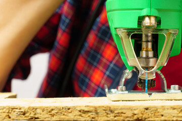 Worker cuts a board with an electric jigsaw.