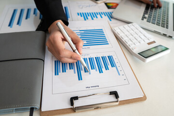 Businessmen are analyzing business graphs on their desks and calculating them using a calculator....