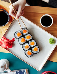 rolls on a white plate with chopsticks on a wooden board top view
