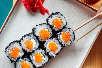 rolls on a white plate with chopsticks on a wooden board top view
