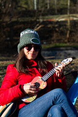 woman playing a ukulele, red coat woman