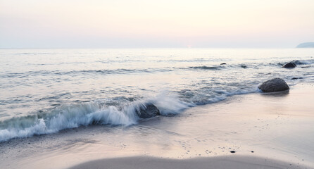 Peaceful sunrise on a beach, focus on rocks, long exposure picture.