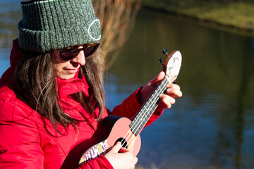 woman playing a ukulele, woman in red coat