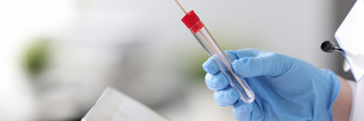 Doctors hand in rubber gloves holding tablet and test tube closeup