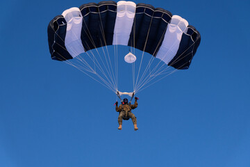 A military skydiver is in the blue sky.