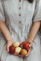 Happy Easter! Woman in rustic linen dress holding natural dyed easter eggs in hands. Aesthetic