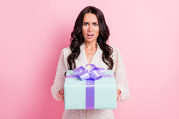 Photo of unhappy displeased young woman get gift dislike shocked amazed isolated on pastel pink color background