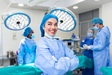 Close-up of a surgeon woman looking at camera with colleagues performing in background in operation room. The concept of medicine