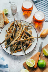close-up of fried fish in a plate next to beer and lime