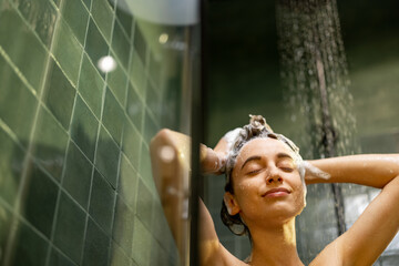 Happy woman with closed eyes in shower rinse shampoo with water dripping on face. Taking shower and...
