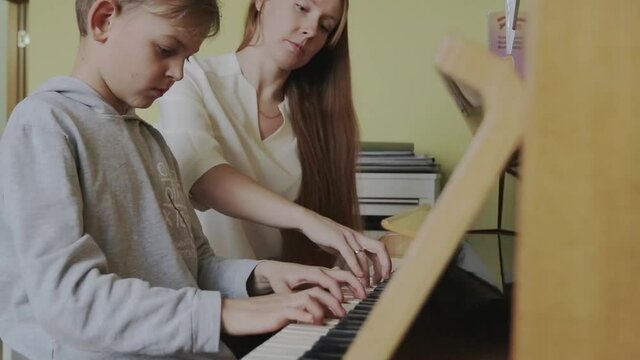  Boy Learning To Play Piano Having Lesson From Female Teacher