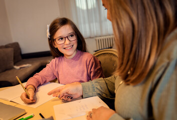 Mother and daughter follow online classes using laptop at home.