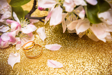 Gold wedding rings and Apple blossoms on a Golden background