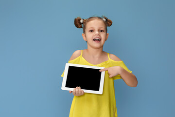 cute little child girl shows empty tablet on blue background