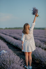 Back view of lovely lady wearing waving white dress, hat. Charming young woman in Blooming Lavender fields. Lavender essential oil with fresh lavender flowers. Lavendula oleum