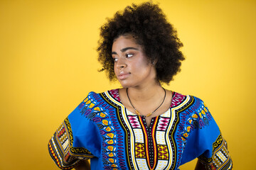 African american woman wearing african clothing over yellow background with a happy face standing and smiling with a confident smile showing teeth