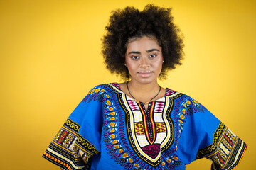 African american woman wearing african clothing over yellow background with a happy face standing and smiling with a confident smile showing teeth