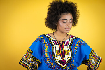 African american woman wearing african clothing over yellow background with a happy face standing and smiling with a confident smile showing teeth