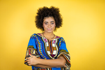 African american woman wearing african clothing over yellow background with a happy face standing and smiling with a confident smile showing teeth