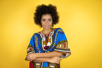 African american woman wearing african clothing over yellow background with a happy face standing and smiling with a confident smile showing teeth