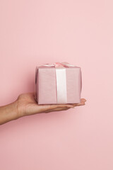 Hand holding gift box on pink background
