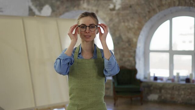 Portrait of a woman put on eyeglasses to start painting in workshop