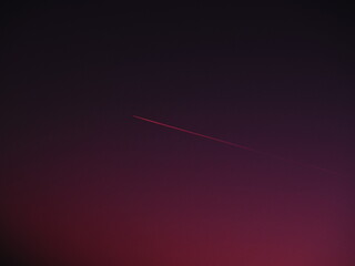 the plane and the trail in the crimson-burgundy sky. Abstract background on space or aero theme