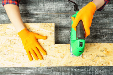 top view, a carpenter works on wood using an electric jigsaw.