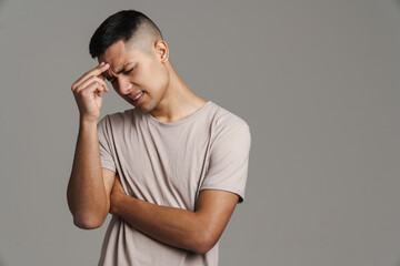 Displeased handsome guy with headache rubbing his forehead
