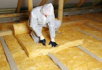 Construction worker installing glass wool