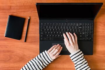 Freelancer workplace top view. Female hands on the keyboard.