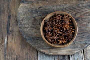 Anise star. Stars in a wooden plate on a brown background. Fragrant seasoning. The bowl is on the rustic table