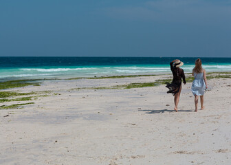 two young girls are walking along the ocean