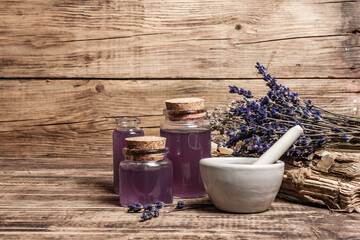 Dried lavender flowers in a in a mortar and pestle with bottle of essential lavender oil or infused water