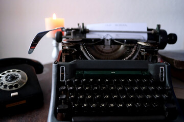 typewriter on table, words fake news are printed on paper in large size, candle is burning, retro...