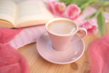 buds of spring flowers, pink tulips, a cup of cappuccino, book on a wooden table, concept of spring, women's lifestyle, morning mood
