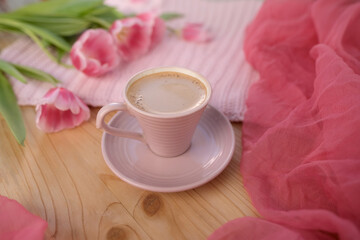 buds of spring flowers, pink tulips, a cup of cappuccino, coffee with cream on a wooden table,...