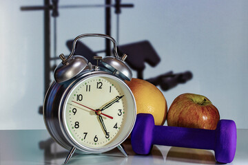 Time for morning workout. Alarm clock on the background of dumbbells. Conception of sports and...